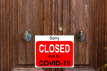 Business center closed due to COVID-19, sign with sorry in door window. Stores, restaurants,...