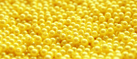 many yellow beads of yellow color on the surface of a dense background, full frame, selected...