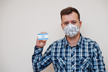 Man in checkered shirt show Israel flag card in hand, wear protect mask isolated on white background. Asian countries Coronavirus concept.