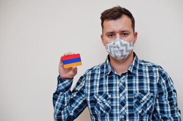 Man in checkered shirt show Armenia flag card in hand, wear protect mask isolated on white background. Asian countries Coronavirus concept.