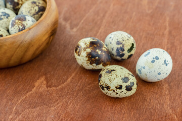 four quail eggs lies on a blackboard against the background of a bowl of breakfast ingredients