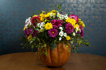 Decorated pumpkin with flowers on the table