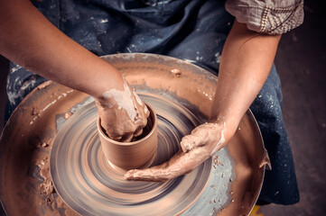 The potter works on a potter's wheel. Concept: handmade, workshop, pottery