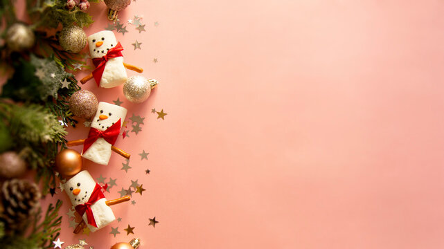 Christmas baner. Marshmellow snowmen with winter decorations over pink background. Copy space