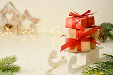 Christmas presents, gift boxes with red bows on sleigh. Winter background with copy space.