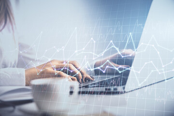Double exposure of woman hands working on computer and forex graph hologram drawing. Financial...