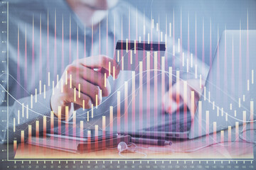 Double exposure of man hands holding a credit card and Forex graph drawing. Stock trading and digital fintech in Internet E-commerce concept.