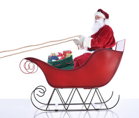 Santa Claus sitting in hi sleigh holidng onto the reins, with a sack of presents at his feet. Isolated on white.