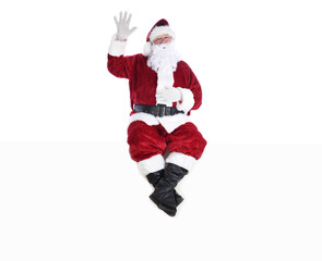 Senior man in traditional Santa Claus Suit sitting on a white wall with one hand in the air and the other on his belly and his eyes closed.