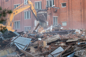 a large excavator breaks down the house, demolishing the house in the city, a lot of dust
