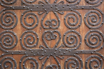 antique brown wooden door decorated with metallic ornaments	