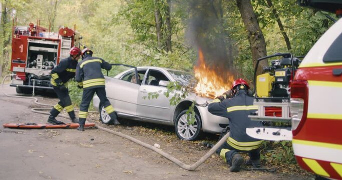 Firefighters saving people from burning car