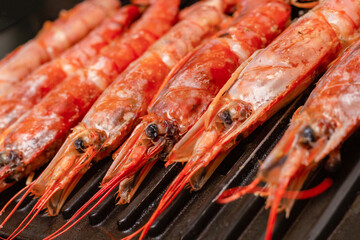 red langoustines background stacked in a row close-up on an iron grill baking pan