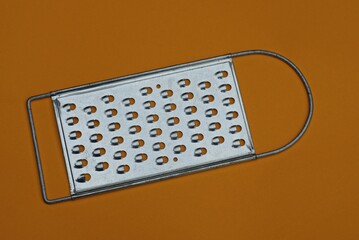 one gray metal grater lies on a brown table