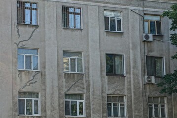 Fototapeta na wymiar texture of a row of windows on a gray wall of an old house on the street