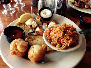 Fototapeta premium A southern seafood platter of grilled shrimp, fish and scallops with hushpuppies and red rice near Charleston, South Carolina, in the heart of the lowcountry.