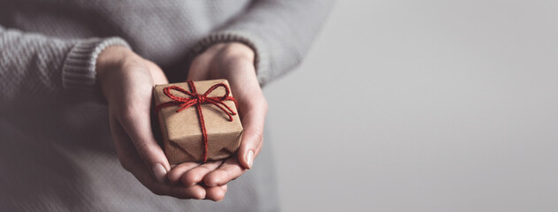 Close up of female hands holding small gift. Sharing concept. Christmas present.	
