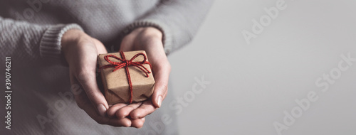 Close up of female hands holding small gift. Sharing concept. Christmas present.