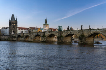 Fototapeta na wymiar View of charles bridge and flowing river vltava in the center of prague at sunset the sky is blue in czech republic