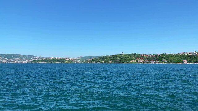 Footage of boats passing on Bosphorus strait in Tarabya area of Istanbul. Kanlica / Beykoz area of Asian side is in the view. It is a sunny summer day. Camera pans left.