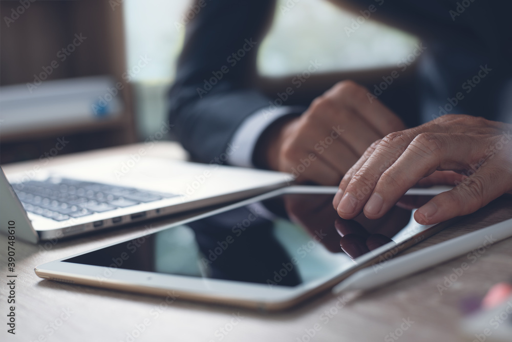 Poster businessman using digital tablet and working on laptop computer in office