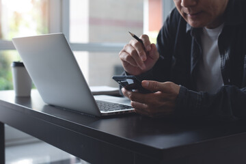 Casual business man using mobile phone during online working on laptop computer from home office