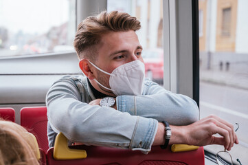 Young man wearing mask and sitting in public transport