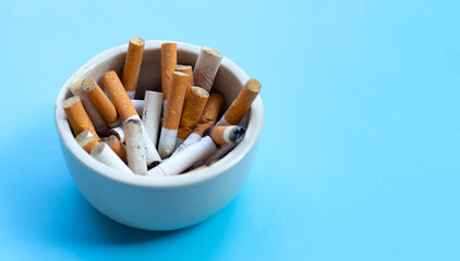 Cigarettes buds in a transparent ashtray on blue background. Copy space