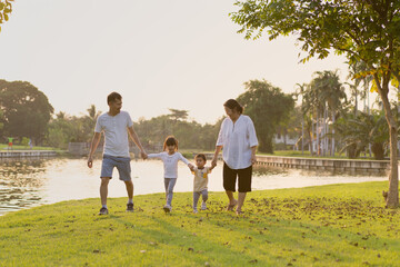 Multigeneration people asian family are walking and holding hands together in the green park, concept of love, relation and love in family lifestyle and simple outdoor activity.
