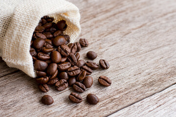 Coffee beans in sack on wood table.