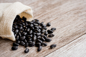 Black beans ( Urad dal, black gram, vigna mungo ) in sack bag isolated on wood table background . 