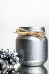 New's Year's decoration. DIY. Christmas candle in silver color with fir cones. Close-up of a silver candle and fir cones. New Year's image. High quality photo