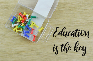 Top view of push pins on wooden background written with text Education Is The Key. Education concept.