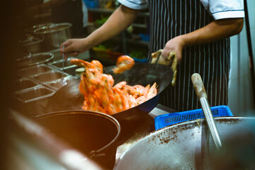 Motion Blur of chef cooking crispy spicy prawns in iron pan, Asian style food.