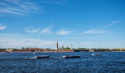 Small tourist ships sail on the Neva River in Saint Petersburg in summer. Peter and Paul fortress. Petersburg architecture. Petersburg museums. Walls of fortress, blue sky, landscape, sunny day.