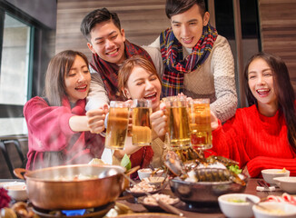 happy friends drinking and toasting beer at hot pot restaurant