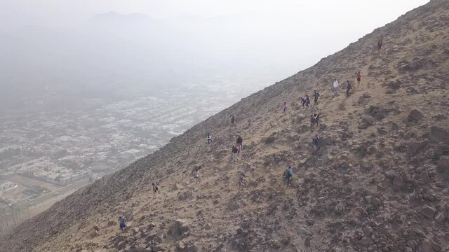 aerial view with drone of people hiking on a hill on a cloudy day. Trekking  in La Vertical Atrapanieblas, La Molina, Lima, Peru.