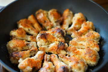 Fried chicken wings. Golden color. In a pan.