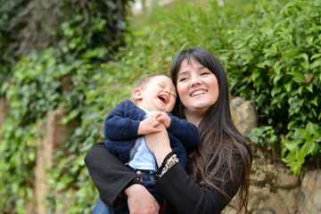 Young Mom Playing With Her Baby In The Park.
Mother Making Her Baby Laugh With Tickles. Family