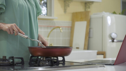 レシピサイトを見ながら料理をする若い女性