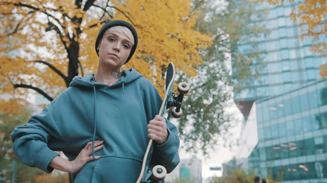 Rebellious teenager, girl, holding the scateboard in the city park in autumn. High quality 4k footage