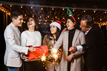 Christmas friends in mexico with sparkler and gifts on a party