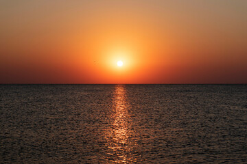 Obraz premium Natural beautiful sunrise over sea and horizon in the morning. Sunlight reflected on calm waves. Seascape under scenic colorful sky sunrise
