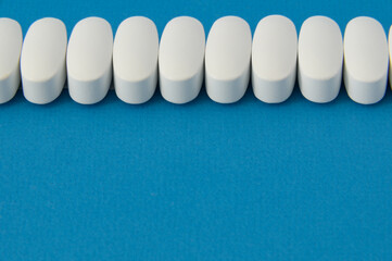many white medical drugs pills on blue background with copy space