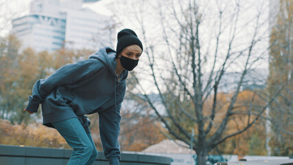 Young blonde woman with face mask skating in the skatepark in autumn. High quality photo