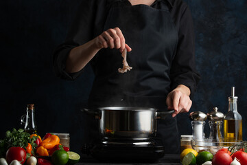 Professional chef cooking traditional asian dish and puts octopus into pot with boiling water. Backstage of preparing seafood on dark blur background. Concept of exotic asian cuisine.