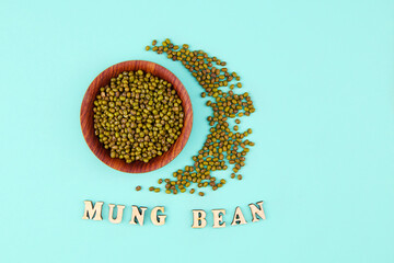 Mung beans in ceramic bowl on a green background.