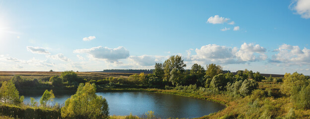 Fototapeta premium Sunny rural landscape with lake and green hills