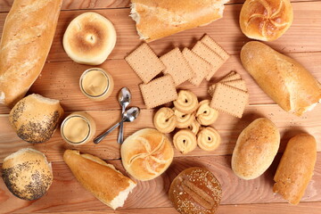 Milk pudding dessert in jar, bread rolls and cookies at wooden plank background. Directly Above.