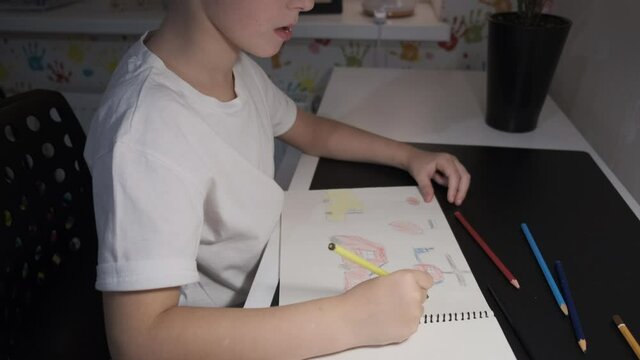 a European child draws with colored pencils at the table